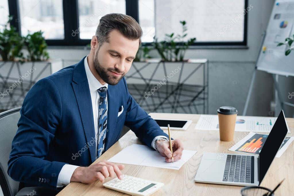 Accountant using a laptop and calculator at an office desk