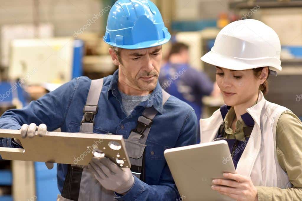 Manufacturing engineers reviewing production data on a tablet on the factory floor
